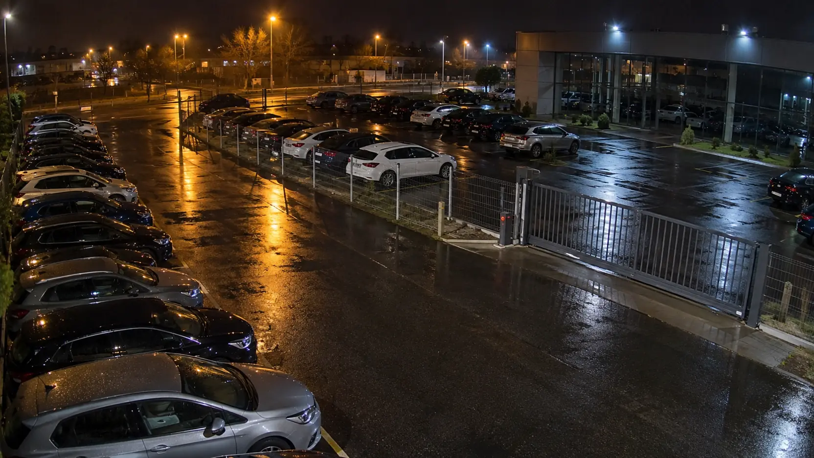 Parc d'une concession automobile fermée, la nuit, vu par une caméra surveillée par l'IA